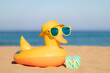 © Sunny studio - Beach flip-flops and yellow duck on the sand against blue sea and sky