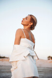 Fototapeta Na drzwi - Gorgeous lady in stylish white suit standing on sand