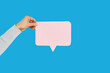 © Studio Romantic - Cropped hand showing blank speech bubble, straight cutting shape, on blue studio background.Information, Thought, Quote And Opinion Concept. Empty space for text or feedback on paper