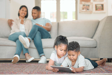 Poster - Were raising children in a modern age. Shot of two young children lying on the floor in the living room and using a digital tablet.