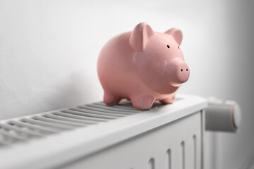 Wall Mural - heating, energy crisis and consumption concept - piggy bank on radiator at home