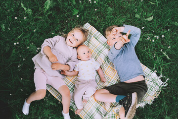 Wall Mural - Children in nature. Preschool small kids play on green grass outdoors in summer. Siblings friendship. Holidays with family. Happy and healthy lifestyle. Minimalist style photo.