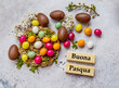 Buona Pasqua   Greeting Card with Easter Chocolate Colorful Eggs and Cherry Blossoms . Happy Easter Text in Italian  Language on Wooden Blocks