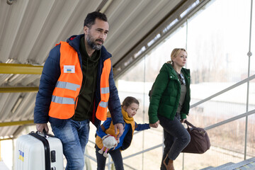 Wall Mural - Volunteer helping Ukrainian mother with child, refugees, at train station.