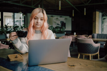 Pretty female student with cute smile keyboarding something on net-book while relaxing after lectures in University, beautiful happy woman working on laptop computer during coffee break in cafe