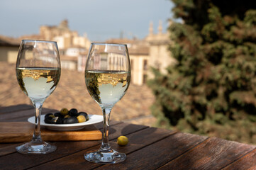 Two glasses of Spanish dry rueda white wine served with olives on roof terrace with view on old part of Andalusian town Granada, Spain