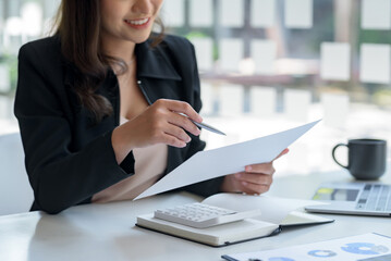 Wall Mural - Close-up of business woman hands check company finances and earnings and budget with graph on desk in the office.