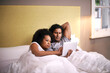 © Mapodile M/peopleimages.com - Who says were too old for a bedtime story. Portrait of a young couple lying in bed using a laptop.