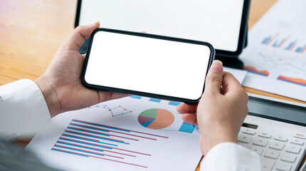 Wall Mural - a businesswoman holding blank screen smartphone over her office desk.