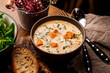 Finnish creamy soup with salmon, potatoes, onions, and carrots in a bowl on the wooden table, selective focus