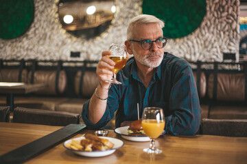 Wall Mural - Mature man in a pub at a table waiting for an order. The client is having lunch at the bar.