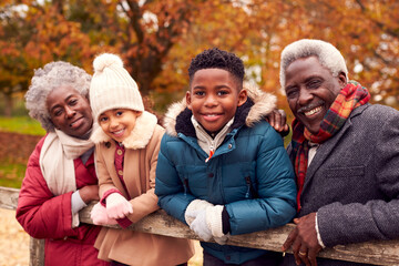 Wall Mural - Portrait Of Grandparents By Gate With Grandchildren On Walk Through Autumn Countryside Together