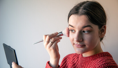 Poster - Portrait of a young woman, the process of doing makeup with brushes.