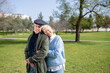 © KAMPUS - Portrait of aged couple standing on green grass. Happy grey-haired man and woman standing close, woman leaning mans shoulder enjoying warmth of sunny day. Love and active rest of aged people concept