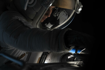 Wall Mural - female astronaut performing spacewalk, working on a outer part of a space craft