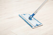 Microfiber mop pad with stick on light laminate background. Floor washing at home, office or other places. Closeup.