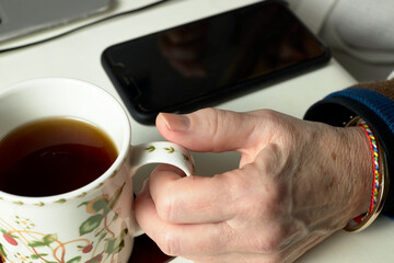 Woman's hand with a cup of tea and electronic gadgets on a table