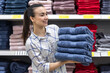 © puhimec - A young woman with a stack of towels in a home improvement store.
