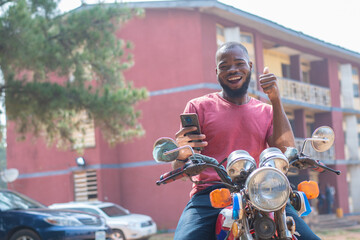 african bike man rejoices while checking his phone