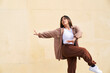Woman dancing in front of beige wall kicking with arm extended