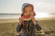 little adorable girl 2 years joyfully on the beach in sunset eating watermelon