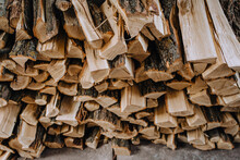 A Lot Of Logs Chopped With An Ax, Dry Firewood Of Acacia, Spruce Stacked In A Row Close-up.