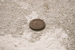 photograph of an 1899 coin in a poorly preserved state on a concrete gray floor