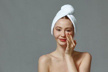 Wall Mural - Young girl with bare shoulders, towel on head apply cream on healthy smooth skin, massage face. Skincare daily routine