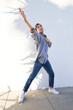 Man dancing by wall with plant shadows arm up