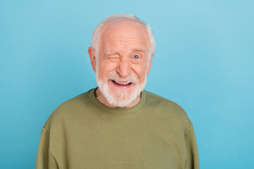 portrait of attractive cheerful coquettish grey-haired man winking isolated over vivid blue color ba