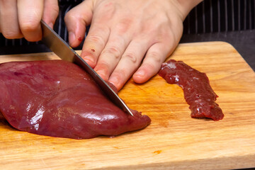 Wall Mural - The cook cuts the calf's liver into slices