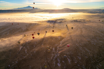 Hot air balloons flying over Cappadocia Goreme National Park Turkey with a view Erciyes mountain; foggy air