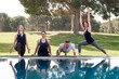 Four adults doing yoga postures in a terrace with pool