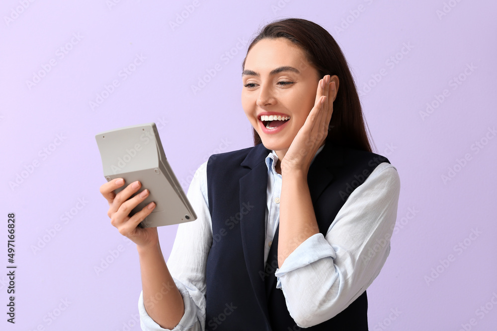 Surprised young businesswoman with calculator on lilac background