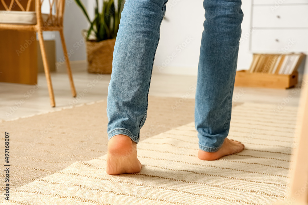 Bare feet of young man walking at home, closeup