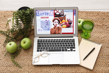 Laptop with eyeglasses, notebook and accessories of blogger on carpet