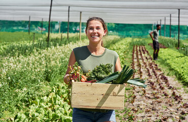 Sticker - Fresh produce coming right up. Portrait of an attractive young woman carrying a crate full of vegetables outdoors on a farm.