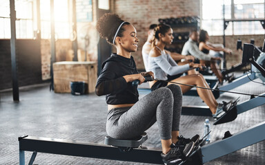 Aufkleber - Working out like a pro. Shot of a young woman working out with a rowing machine in the gym.