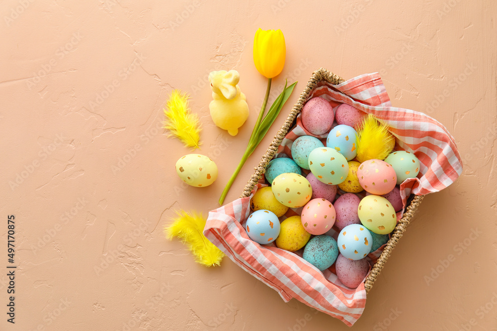 Basket with painted Easter eggs, bunny and tulip flower on beige background