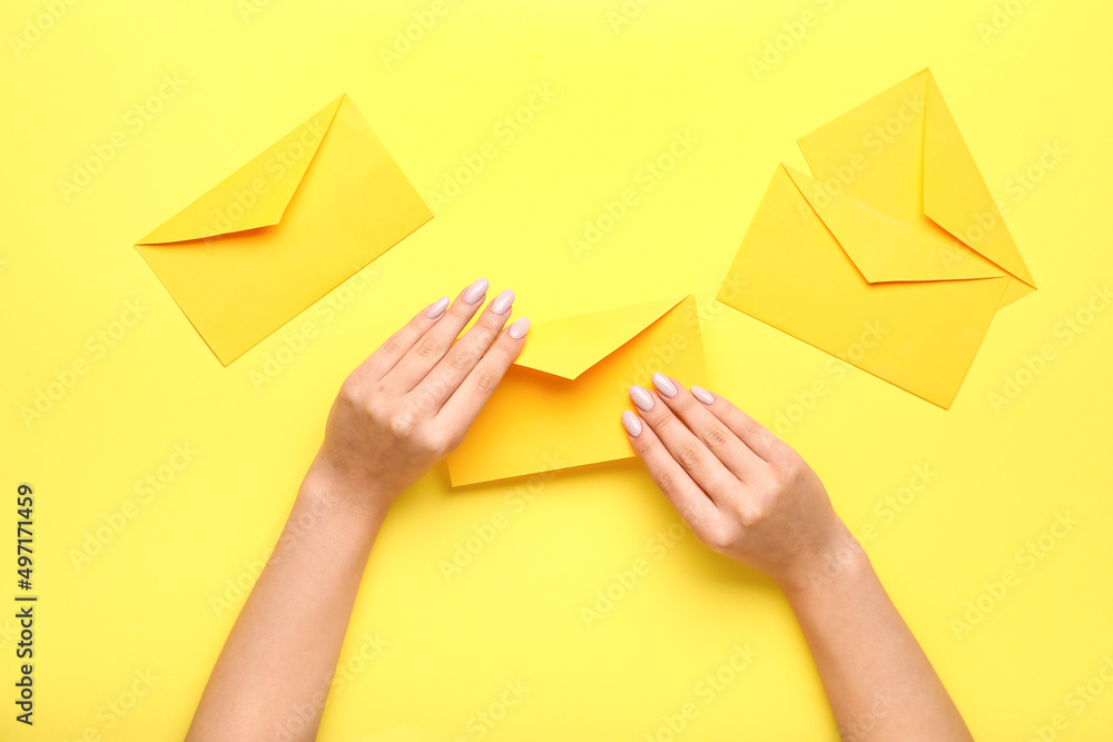 Female hands with beautiful manicure and envelopes on yellow background