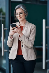 Wall Mural - Another good review from a client. Cropped shot of an attractive mature businesswoman standing alone and using her cellphone in her home office.