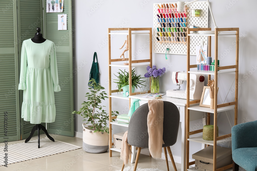 Interior of stylish atelier with tailor's workplace, shelving units and pegboard