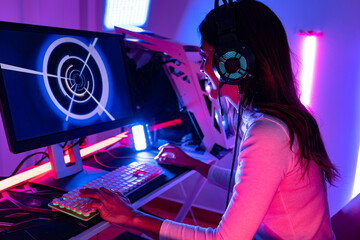 Wall Mural - young  playing game online at home. Gamer  controlling joystick for video game. Teenage girls leisure game in neon light room at home.