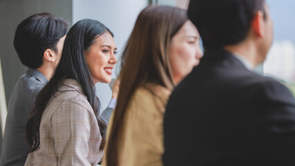 Asian young professional successful businessman and businesswoman colleagues in formal business suit sitting at cafeteria table talking chatting together during coffee break after conference meeting