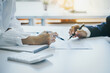 © Phushutter - Close-up of two businesswomen calculating financial statements at a desk.