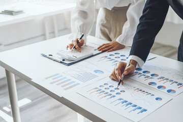 Close-up of two businesswomen calculating financial statements at a desk.