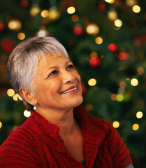 Sticker - Christmas contemplation. Shot of a mature woman looking thoughtful in front of a Christmas tree.