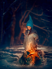 Girl gnome in the night winter forest with a glowing star