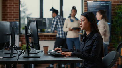 Wall Mural - asian software developer holding clipboard sitting down and starting to type on computer keyboard. m