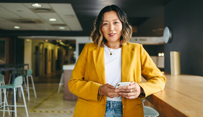 Ethnic businesswoman holding a smartphone in a co-working office